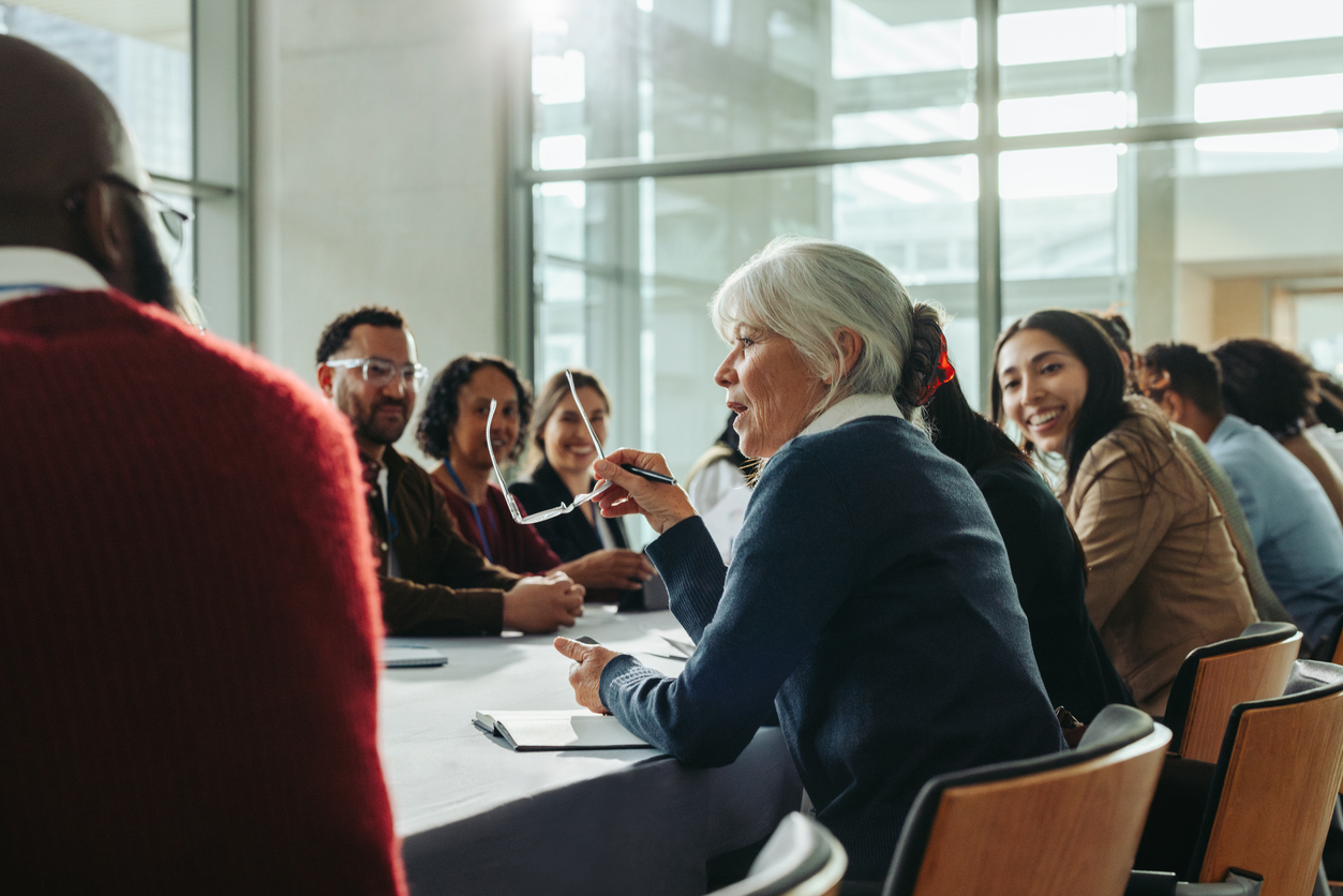 Diverse group of business professionals in a meeting with a woman speaking